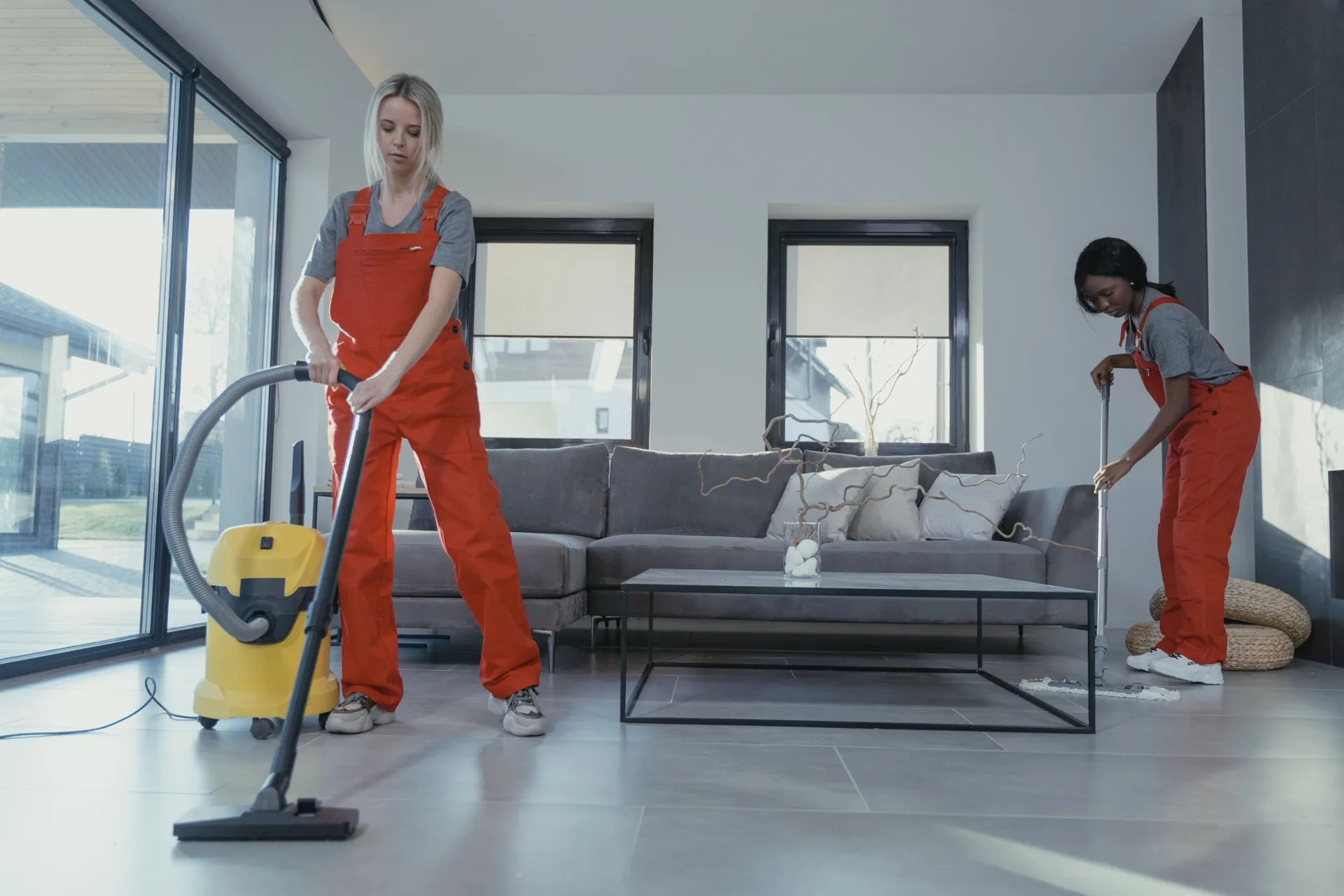 Two cleaners tidying a bright modern living room
