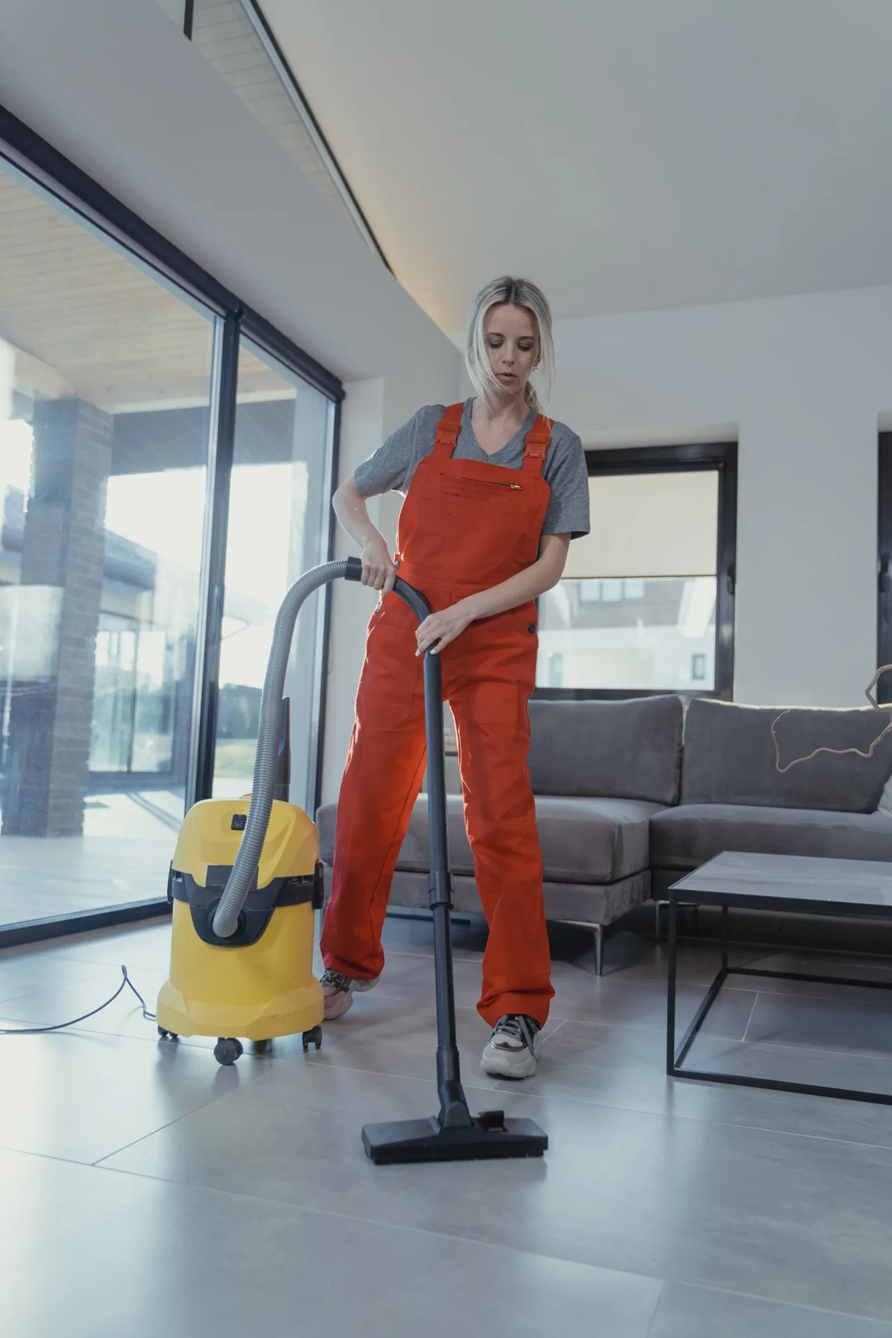 Cleaner vacuuming the floor in a modern living room